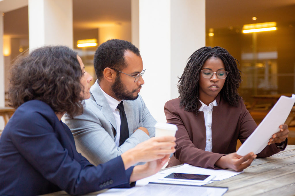 Legal expert explaining contract specifics A legal expert explains the details of a written contract to two business people.